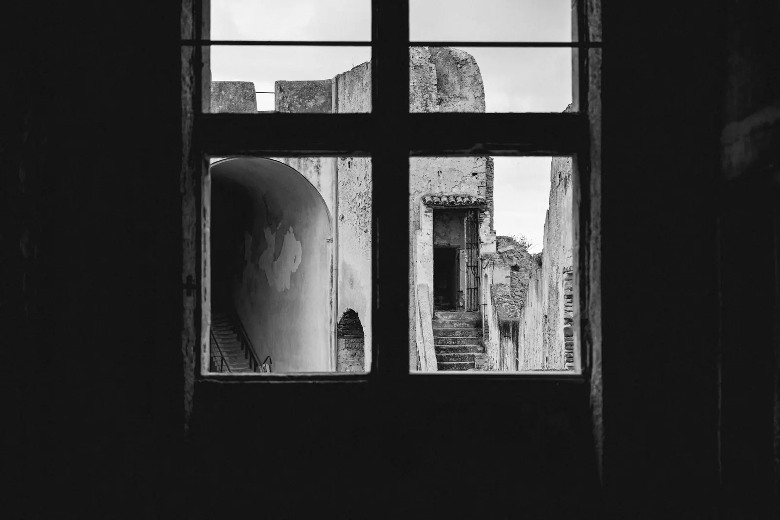 Window of an abandoned room looking onto ruined walls