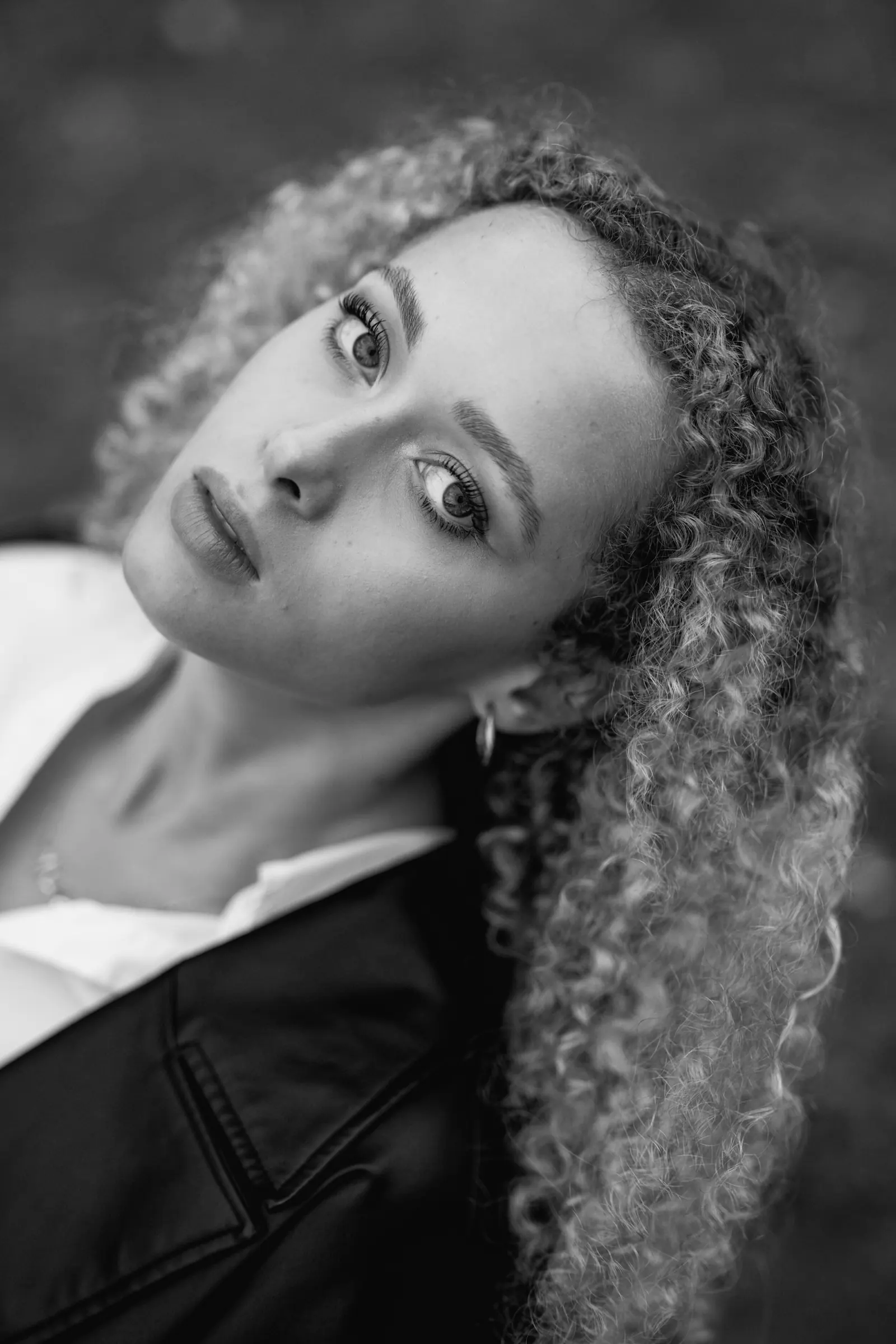 Woman with curly hair tilting her head, in black and white