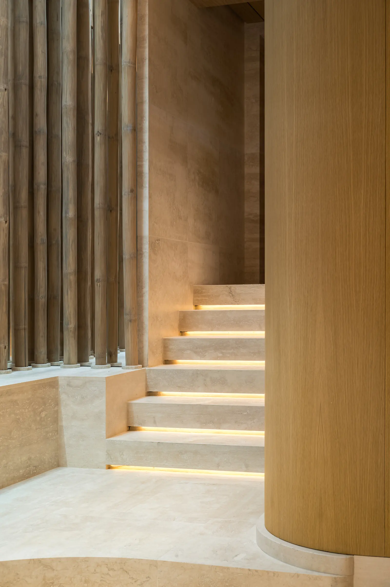 Stone staircase lit from below beside a curved oak column