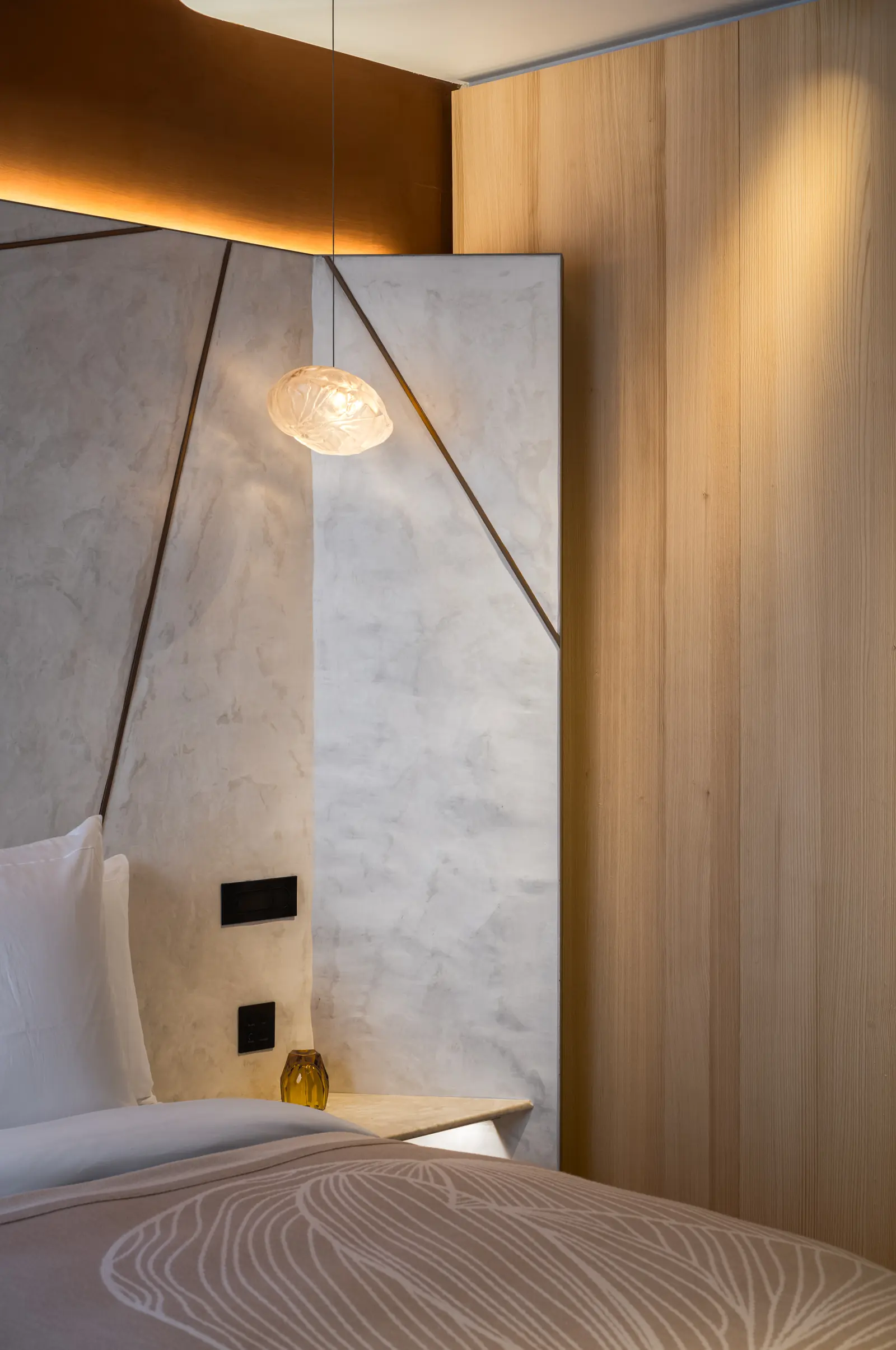 Bed with a marble headboard panel and a glass pendant lamp