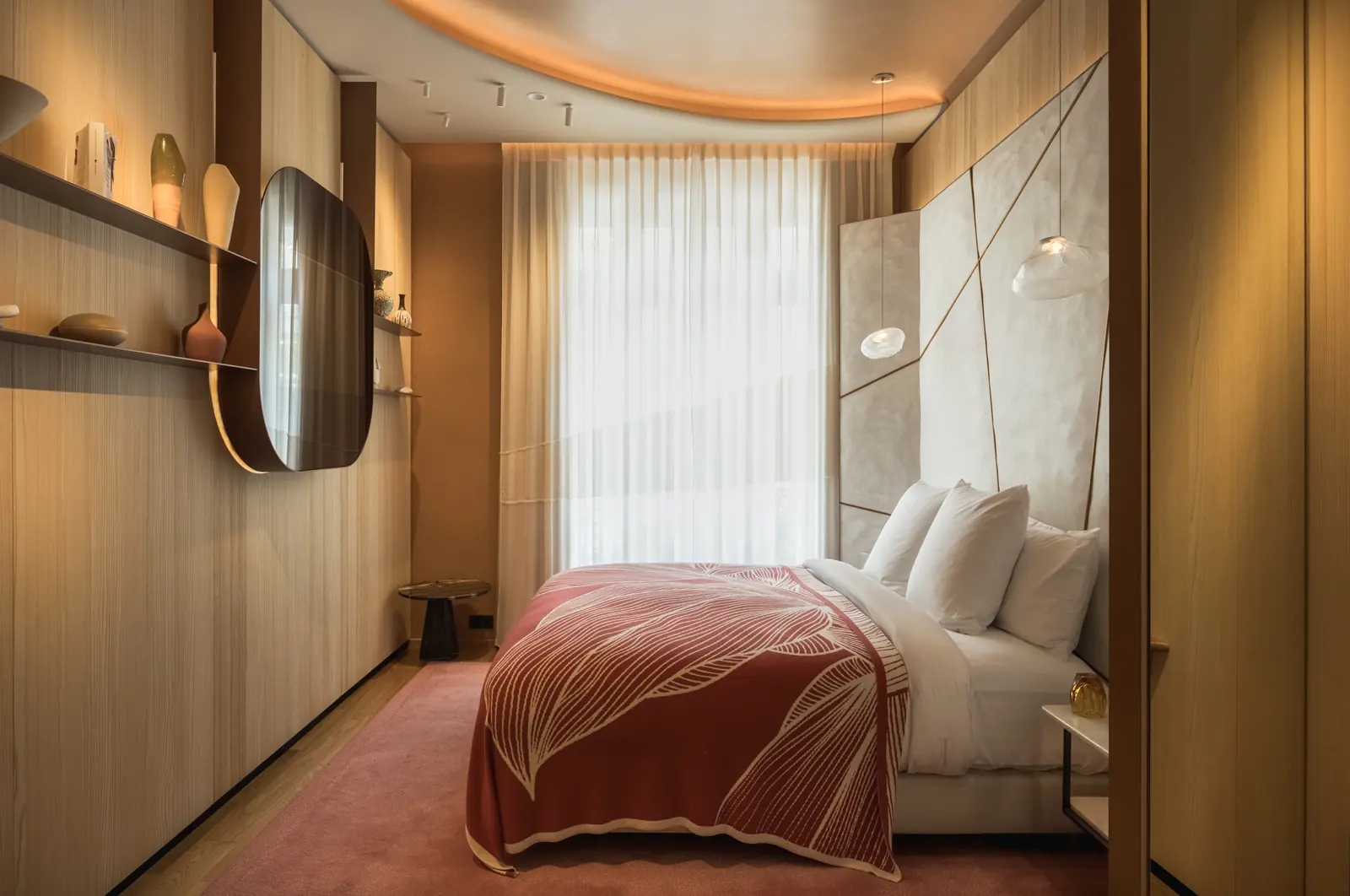 Bedroom with a red bedspread, oak panelling and a curved ceiling light