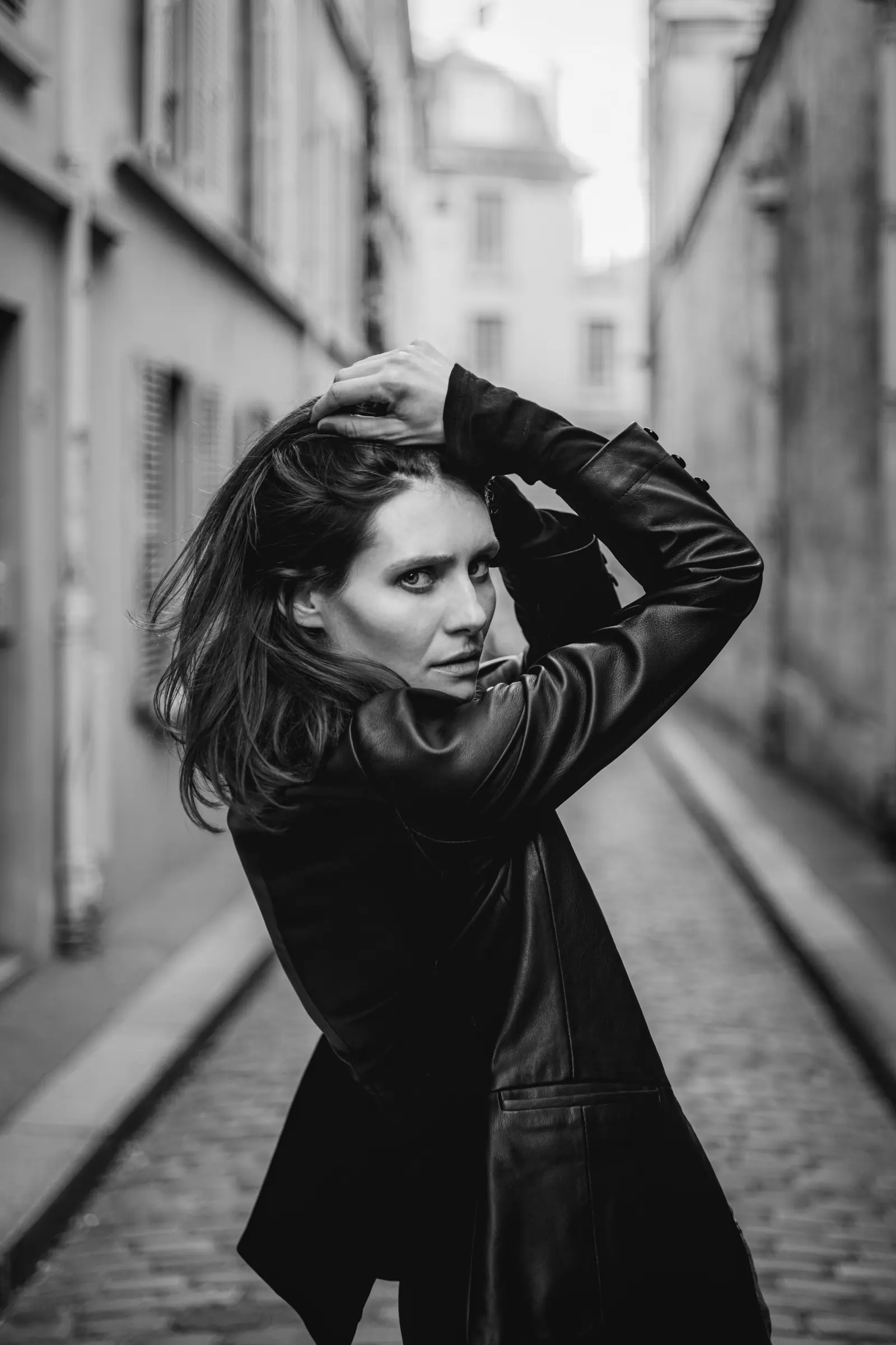 Woman turning back in a cobbled alley, in black and white