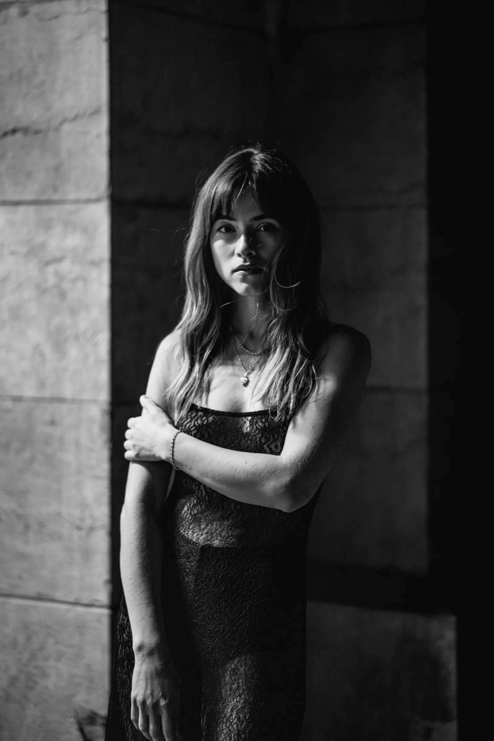 Woman in a slip dress standing under a stone arch, in black and white
