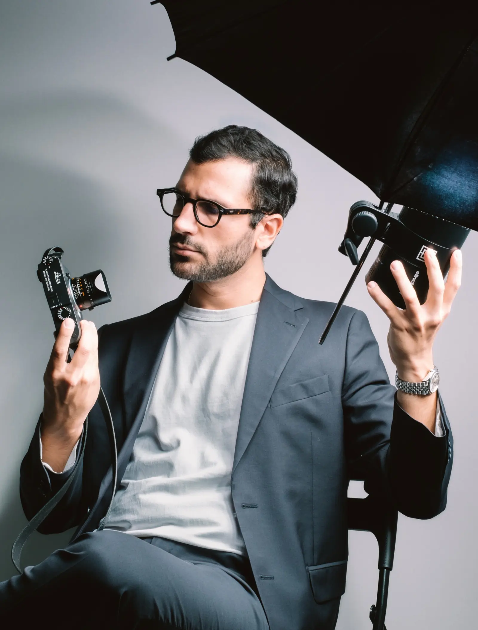 Flavio Francesco Dario holding a Leica camera and a flash head under an umbrella